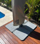 A grey granite cantilever umbrella ballast weight with a smooth texture surface. Photo of four weights on a standard powder-coated steel cross frame.